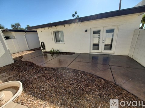 A patio area with a white building and a gravel ground.