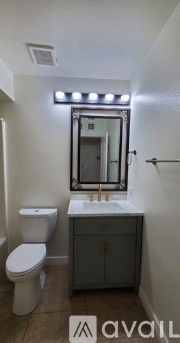 A bathroom with a toilet, sink, and mirror.
