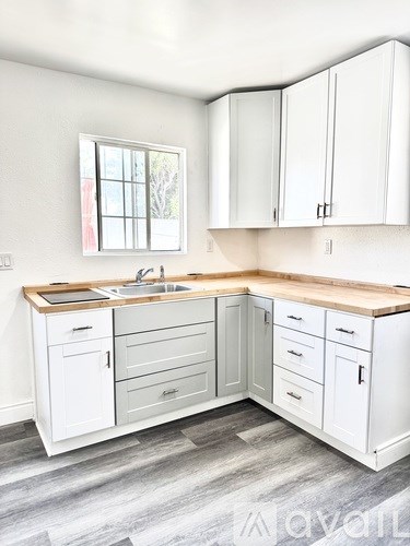 A kitchen with white cabinets and a wooden countertop.