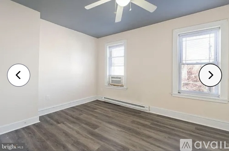 A room with a ceiling fan and two windows.