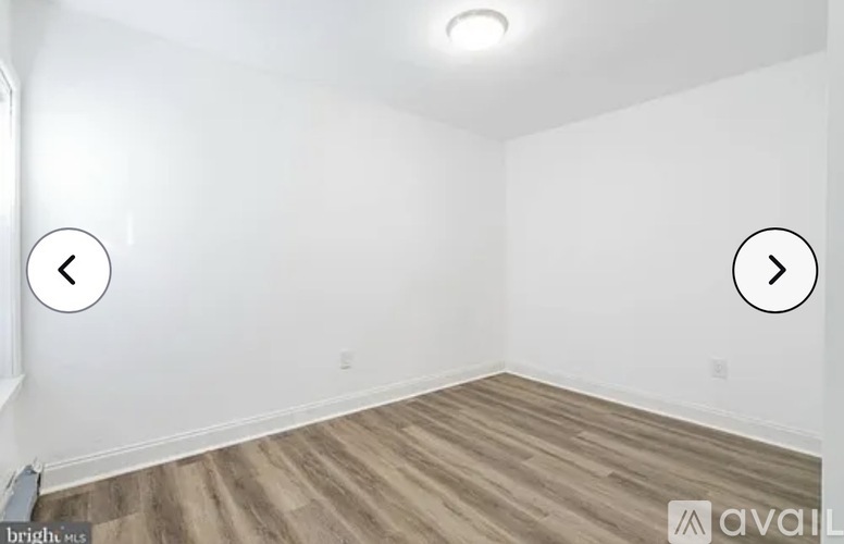 A room with wooden flooring and white walls, with a left and right arrow indicating the room can be viewed in different directions.