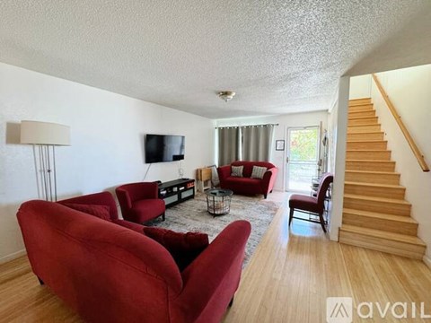 A living room with red chairs and a flat screen TV.