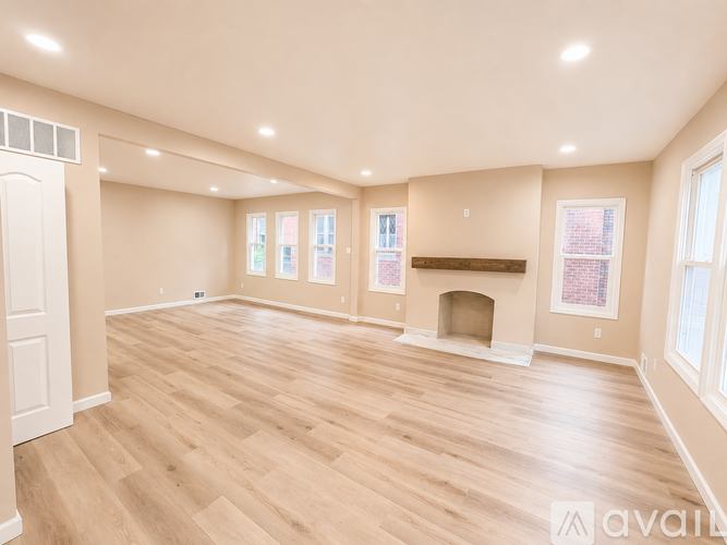 A spacious room with wooden flooring and a fireplace.