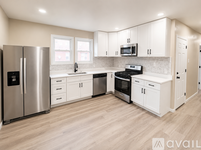 A kitchen with white cabinets and a stainless steel refrigerator.