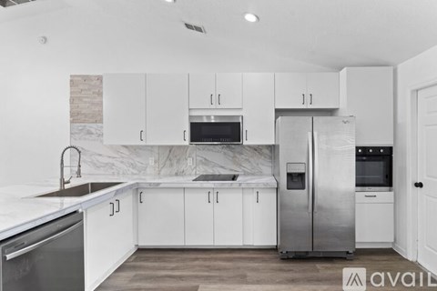 A kitchen with white cabinets and a marble backsplash.