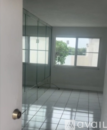 A room with white tiled flooring and a window overlooking a body of water.