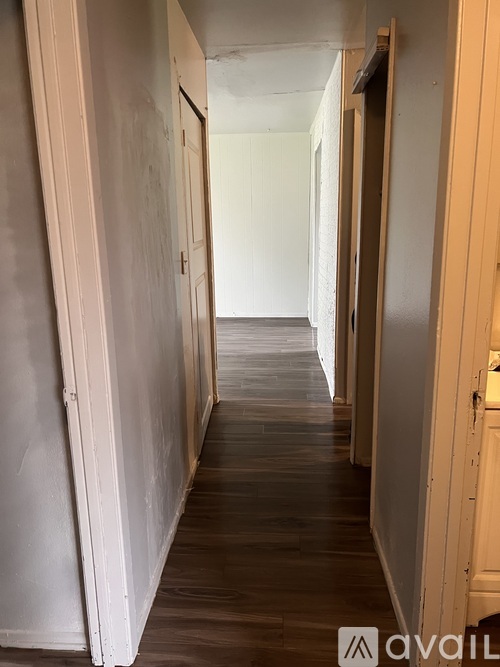 A long hallway with white walls and wood floors.