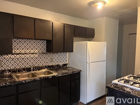A kitchen with a white fridge and black cabinets.