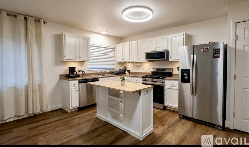 A kitchen with white cabinets and a wooden island.