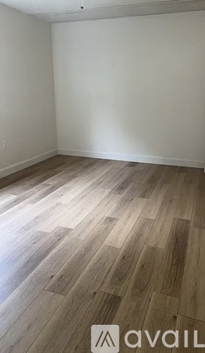 A room with wooden flooring and a white wall.