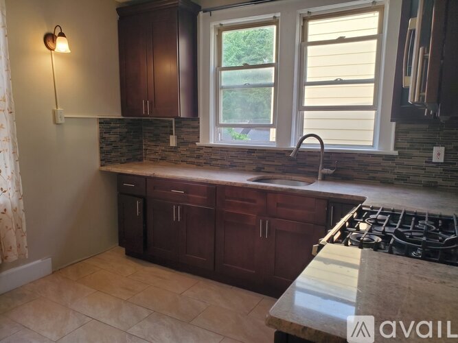A kitchen with dark wood cabinets and a granite countertop.