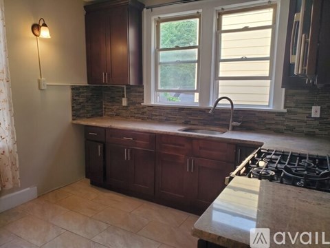 A kitchen with dark wood cabinets and a granite countertop.
