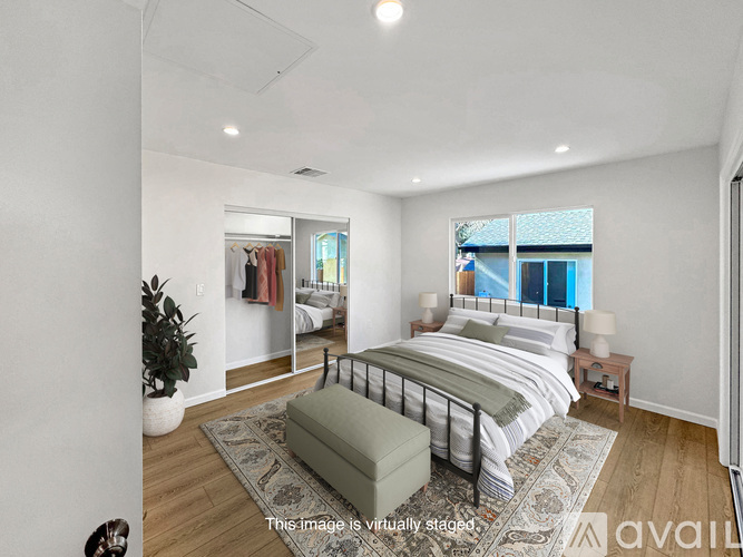 A bedroom with a large bed and a green ottoman.
