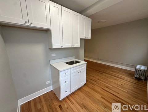 A kitchen with white cabinets and a wooden floor.
