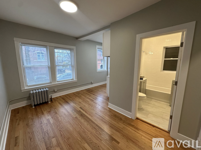 A room with wooden floors and a window with a view of a building outside.