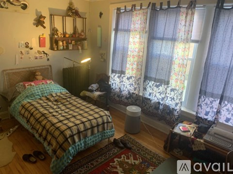 A bedroom with a bed, a dresser, a window with curtains, and a rug on the floor.