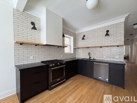 A kitchen with black cabinets and a white brick wall.