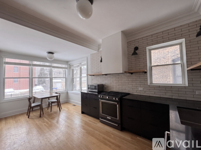 A kitchen with a brick wall and wooden floors.