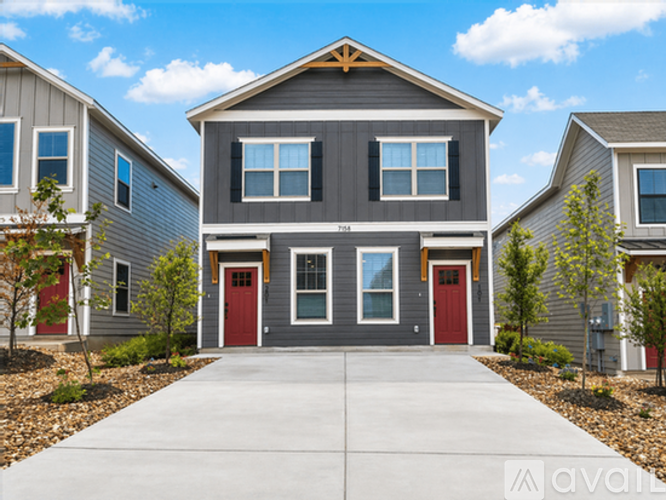 A grey house with a red door in the front.