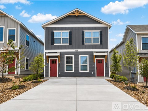 A grey house with a red door in the front.