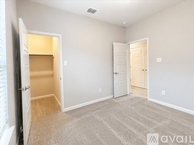 A spacious room with a carpeted floor and two doors.