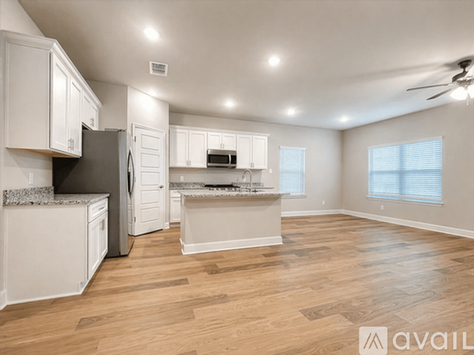 A spacious kitchen with white cabinets and a wooden floor.
