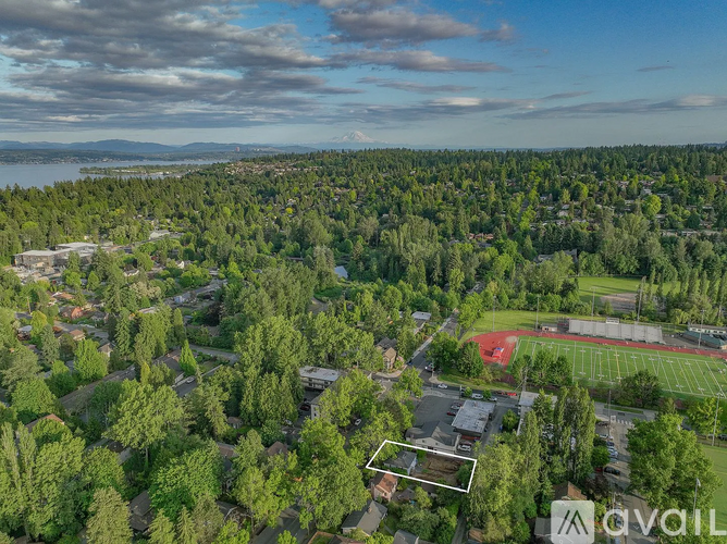 An aerial view of a forested area with a sports field and buildings.