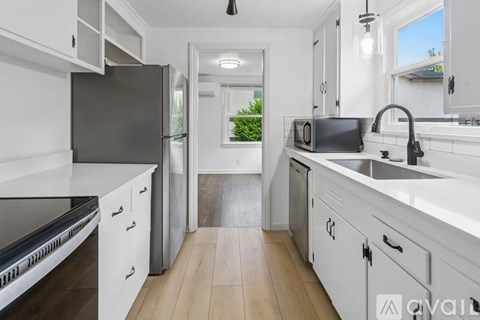 A kitchen with white cabinets and a black refrigerator.