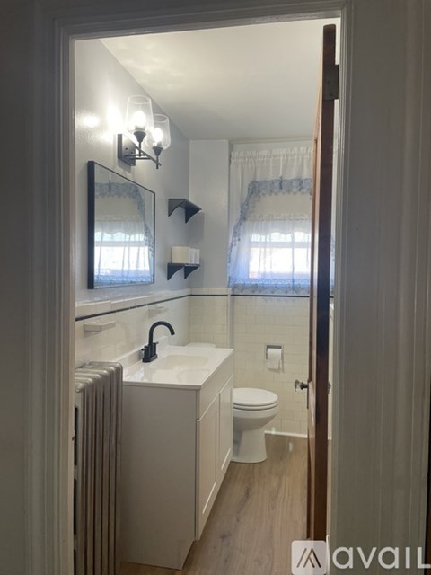 A bathroom with a toilet, sink, and a window.