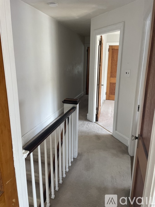A hallway with a white door and a black railing.
