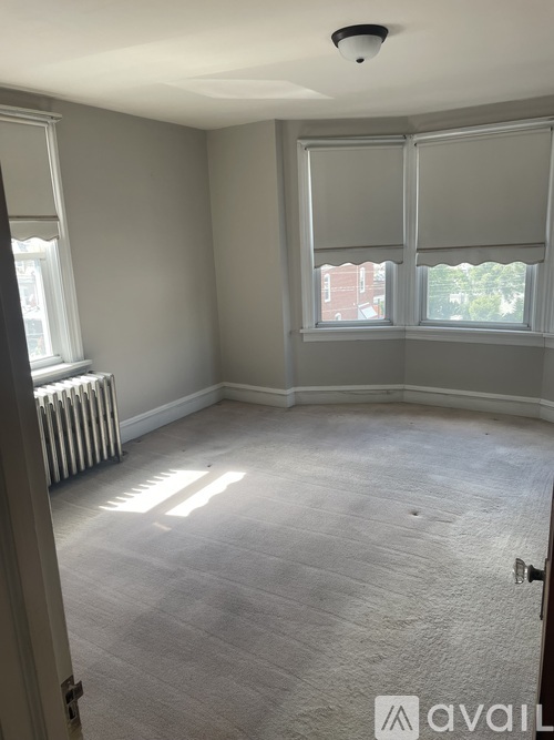 A room with a carpeted floor and a window with blinds.