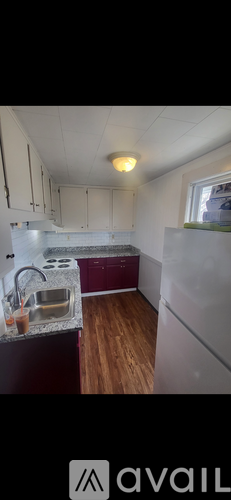 A kitchen with white cabinets and a maroon counter.