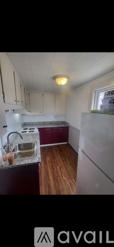 A kitchen with white cabinets and a maroon counter.