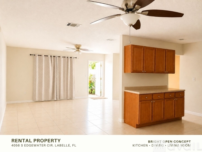 A spacious living room with a ceiling fan and a cabinet.