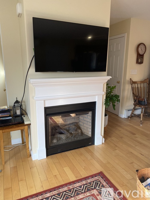 A large black screen TV mounted above a fireplace in a living room.