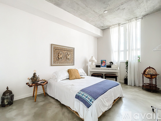 A bedroom with a large bed and a painting on the wall.