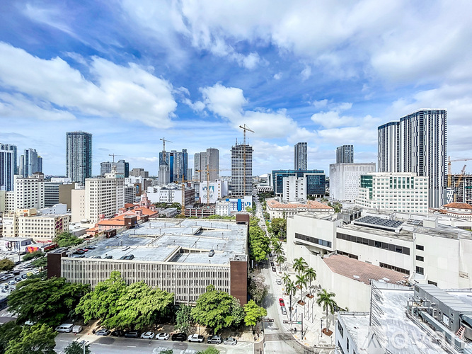 A cityscape with a mix of modern and older buildings under a partly cloudy sky.