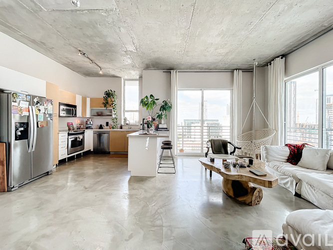 A modern kitchen with a refrigerator, sink, and a dining area with a white couch.