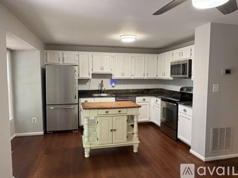 A kitchen with white cabinets and a wooden island.
