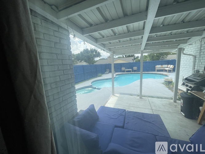 A patio with a pool and a blue cushioned chair.