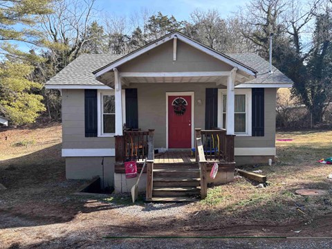 A small house with a red door and a porch.