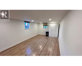 A spacious room with wooden flooring and white walls.