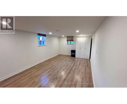 A spacious room with wooden flooring and white walls.