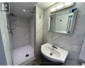 A bathroom with a sink, mirror, and shower.