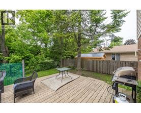 A backyard with a wooden deck, a grill, and a green fence.