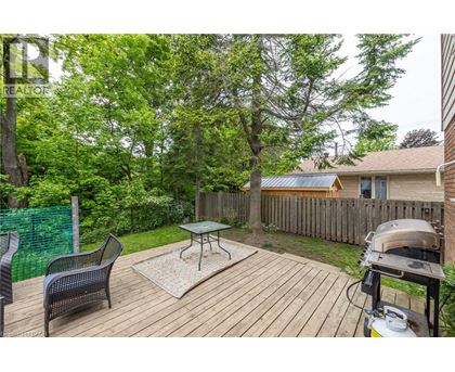 A backyard with a wooden deck, a grill, and a green fence.