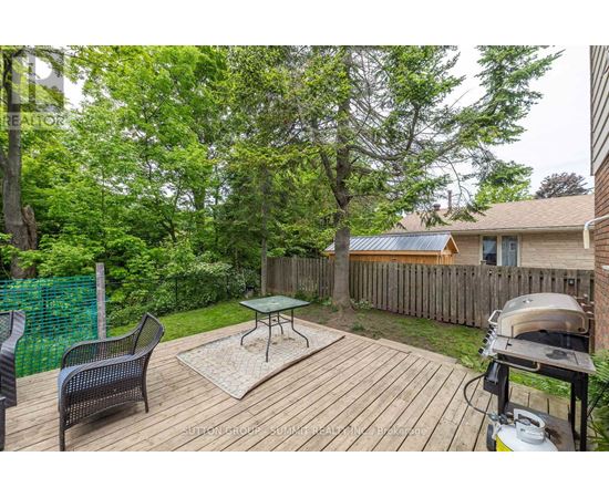 A backyard with a wooden deck, a grill, and a green fence.