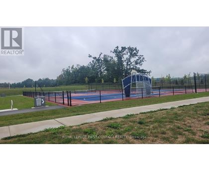 A basketball court is surrounded by a fence and there is a trash can in the foreground.