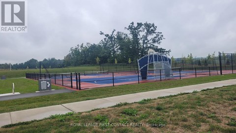 A basketball court is surrounded by a fence and there is a trash can in the foreground.