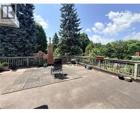 A patio with a chair and table is surrounded by a fence and trees.